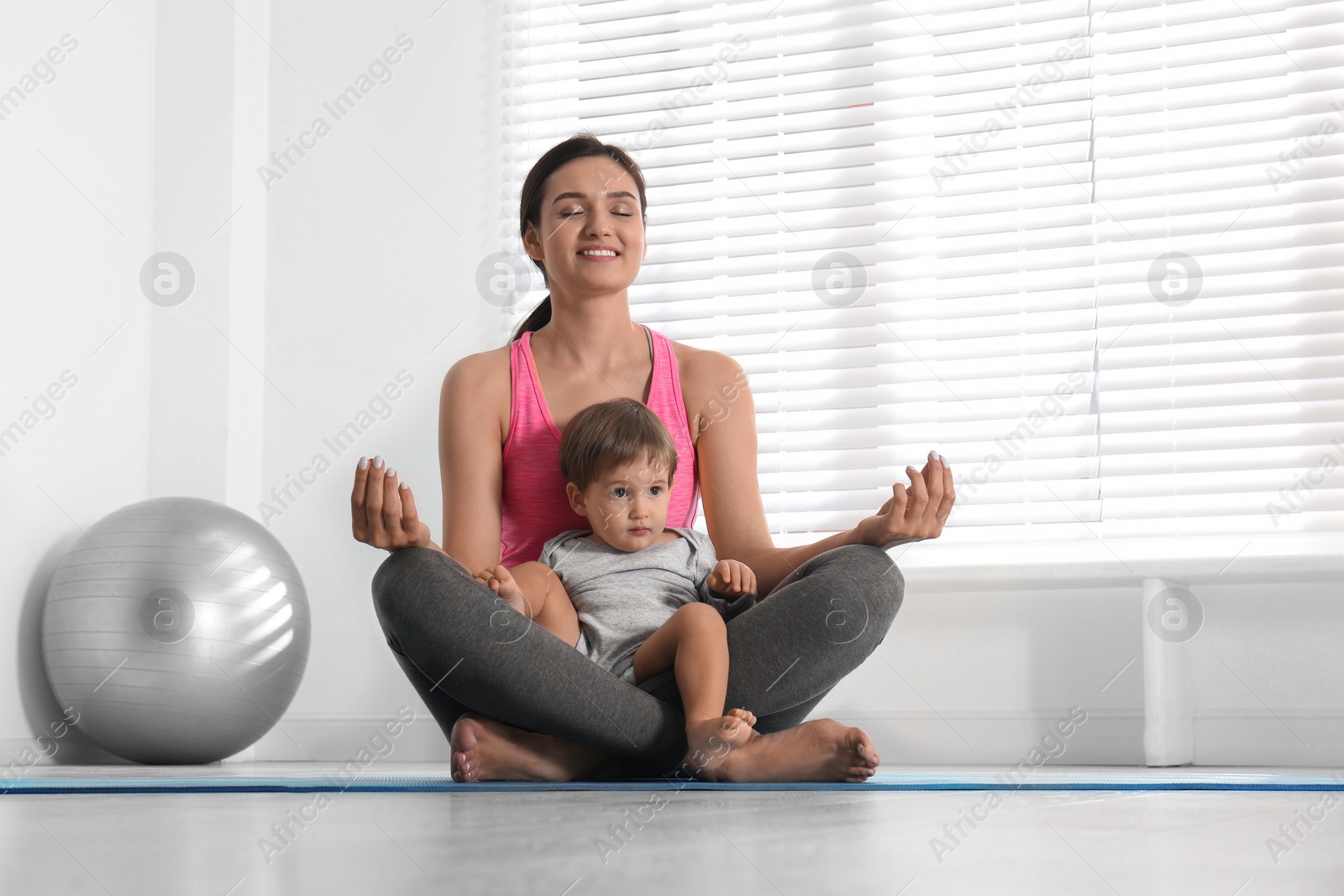 Photo of Young woman meditating with her son at home