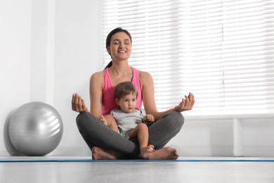 Photo of Young woman meditating with her son at home