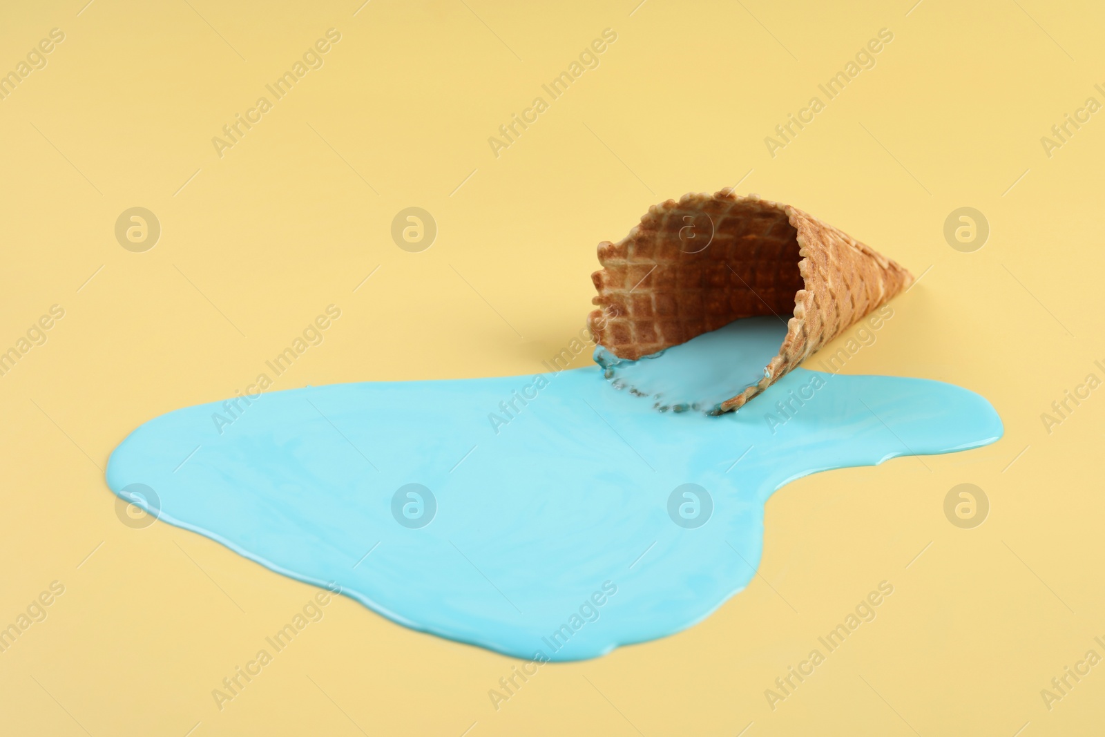 Photo of Melted ice cream and wafer cone on beige background. Space for text