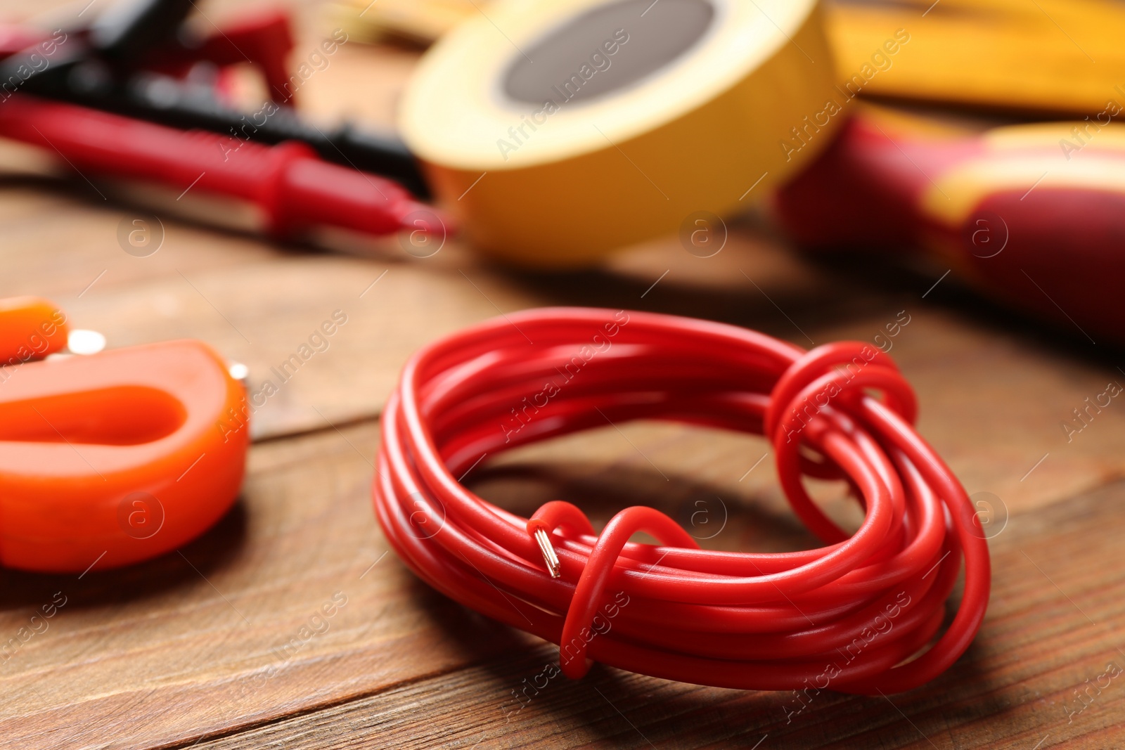 Photo of Electrical wire and tools on wooden table, closeup