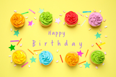 Image of Delicious cupcakes and text Happy Birthday on yellow background, flat lay