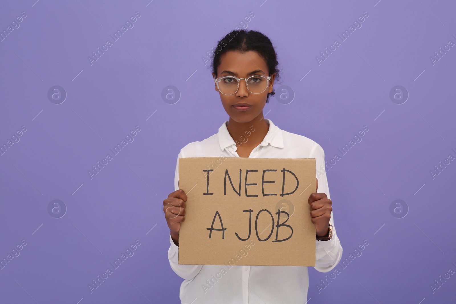 Photo of Unemployed African American woman holding sign with phrase I Need A Job on violet background