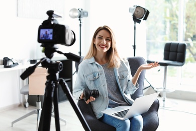 Female photo blogger recording video on camera indoors