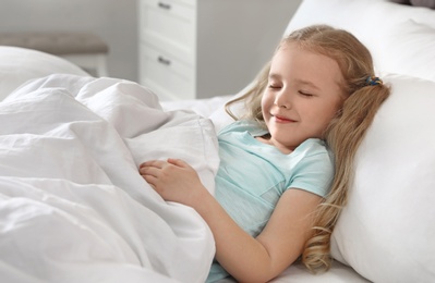 Photo of Portrait of cute little girl sleeping in large bed