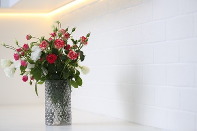 Photo of Vase with beautiful flowers on white countertop in kitchen, space for text