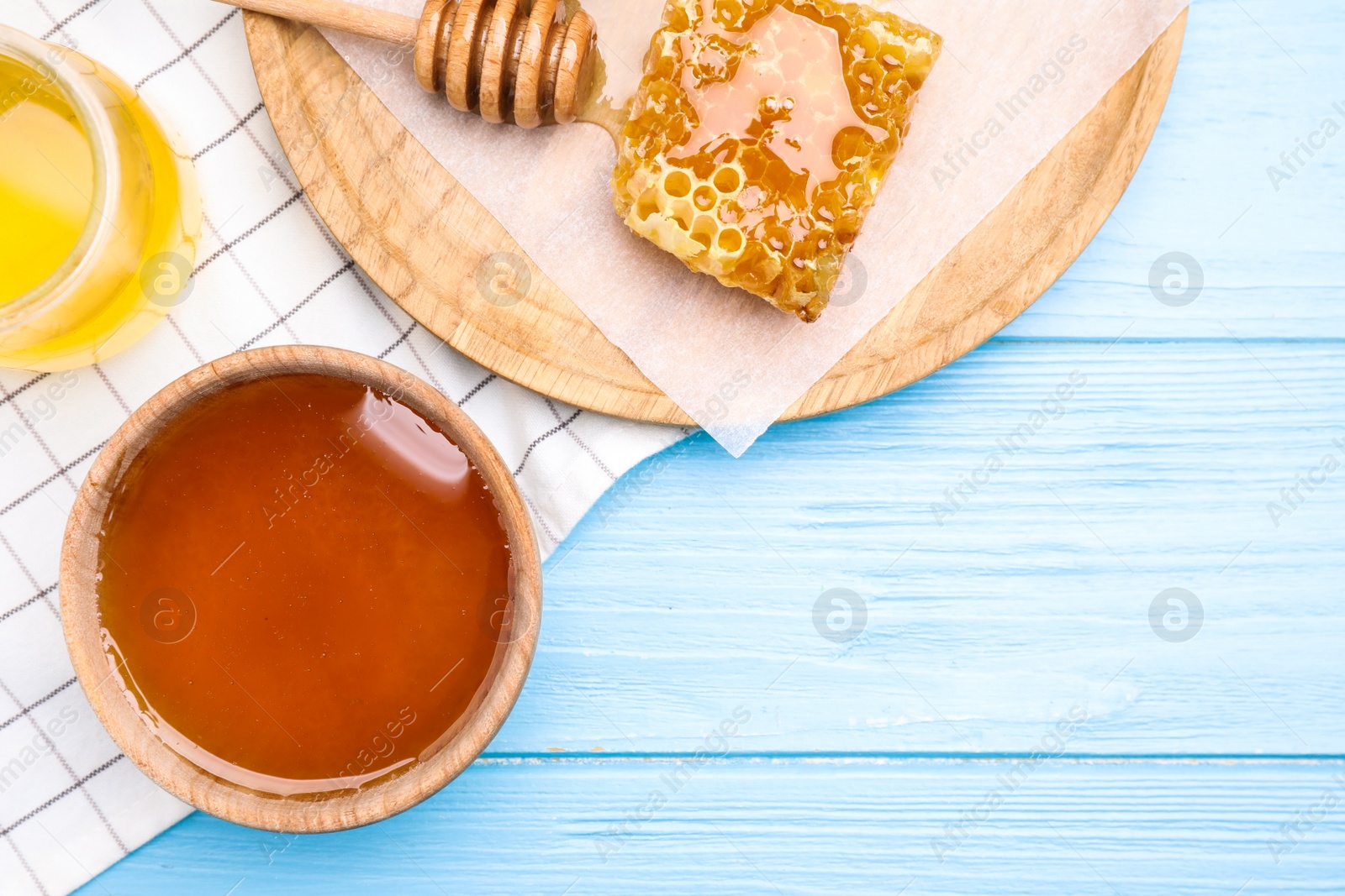 Photo of Tasty honey on light blue wooden table, flat lay. Space for text