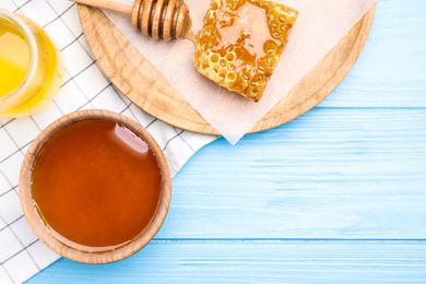 Tasty honey on light blue wooden table, flat lay. Space for text