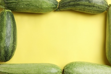 Photo of Fresh ripe green zucchinis on yellow background, flat lay. Space for text