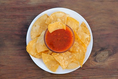 Photo of Tasty salsa sauce and tortilla chips on wooden table, top view