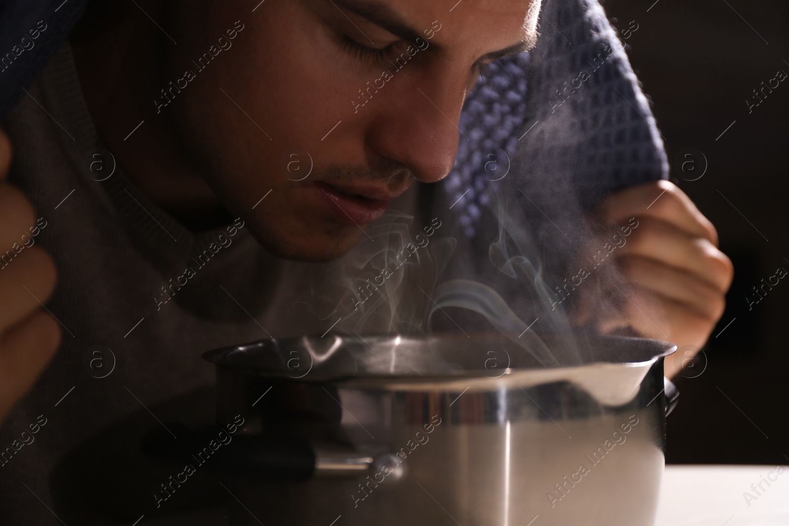 Photo of Man with plaid doing inhalation above saucepot, closeup