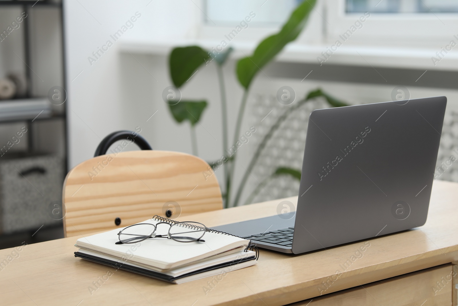 Photo of Home workspace. Laptop, glasses and stationery on wooden desk in room