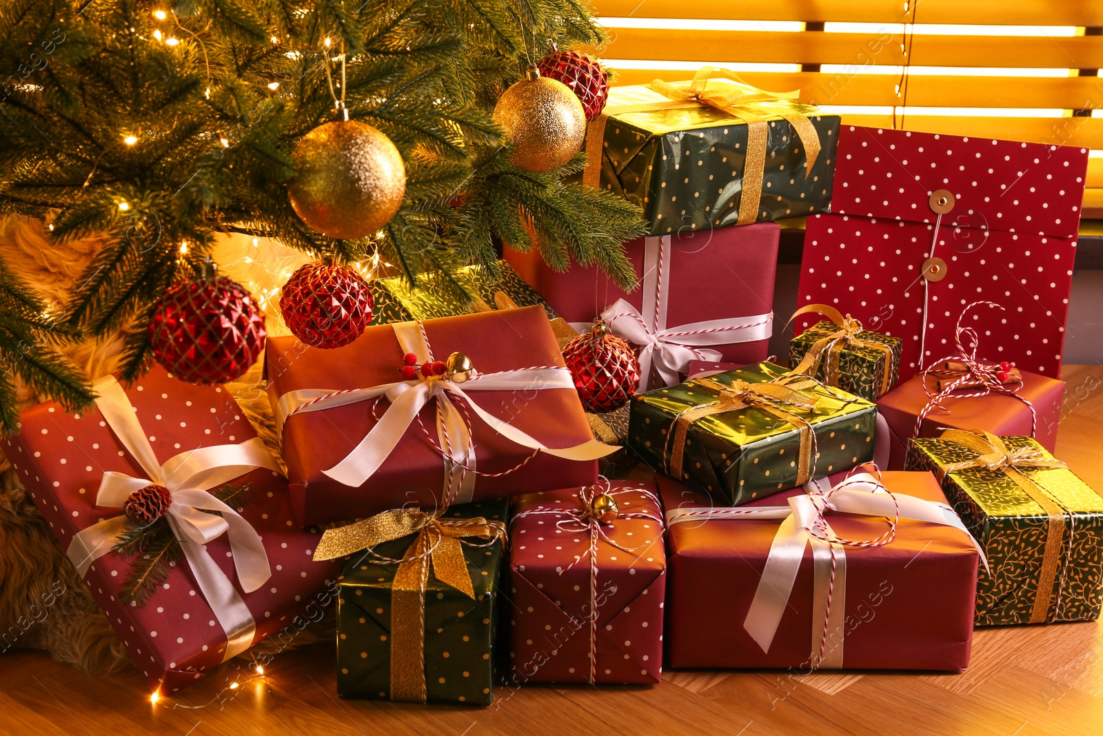 Photo of Pile of gift boxes near decorated Christmas tree indoors