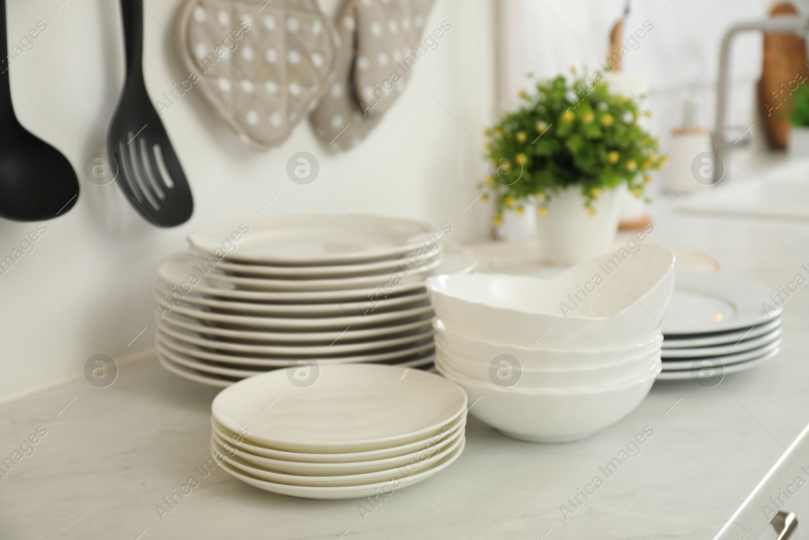 Photo of Clean plates and bowls on white marble countertop in kitchen