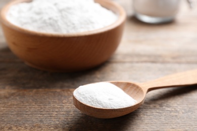 Spoon with baking soda on wooden table