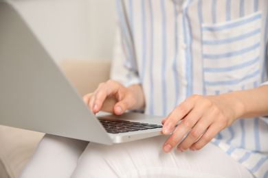 Photo of Young woman with laptop sitting indoors, closeup