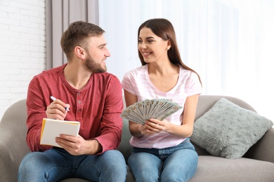 Beautiful young couple with money at home