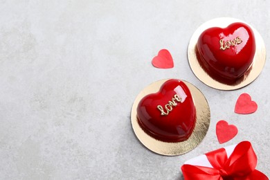 Photo of St. Valentine's Day. Delicious heart shaped cakes and gift on light table, flat lay. Space for text