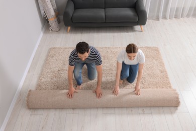 Photo of Couple unrolling carpet on floor in room