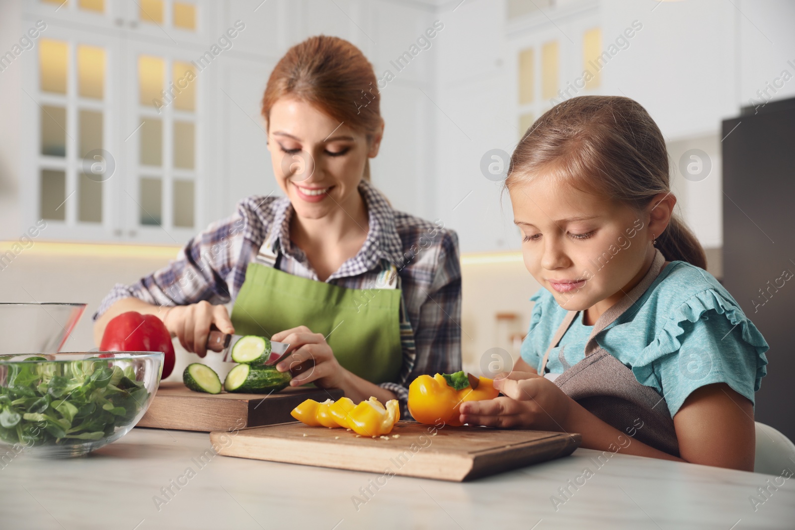 Photo of Mother and daughter cooking salad together in kitchen