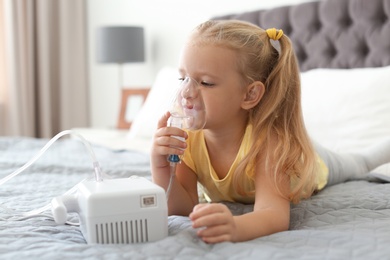 Photo of Little girl using asthma machine in bedroom. Space for text