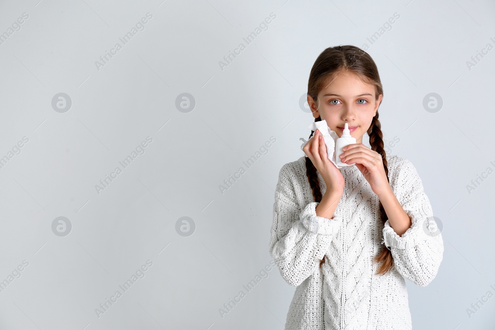 Photo of Sick little girl using nasal spray on white background. Space for text