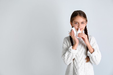 Photo of Sick little girl using nasal spray on white background. Space for text