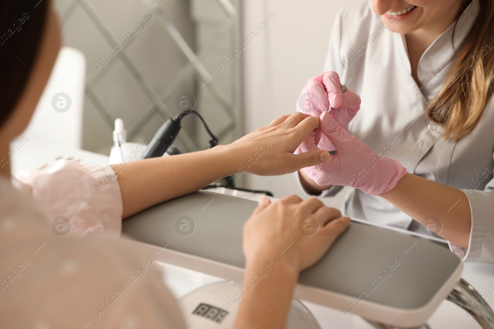 Photo of Professional manicurist working with client in beauty salon, closeup