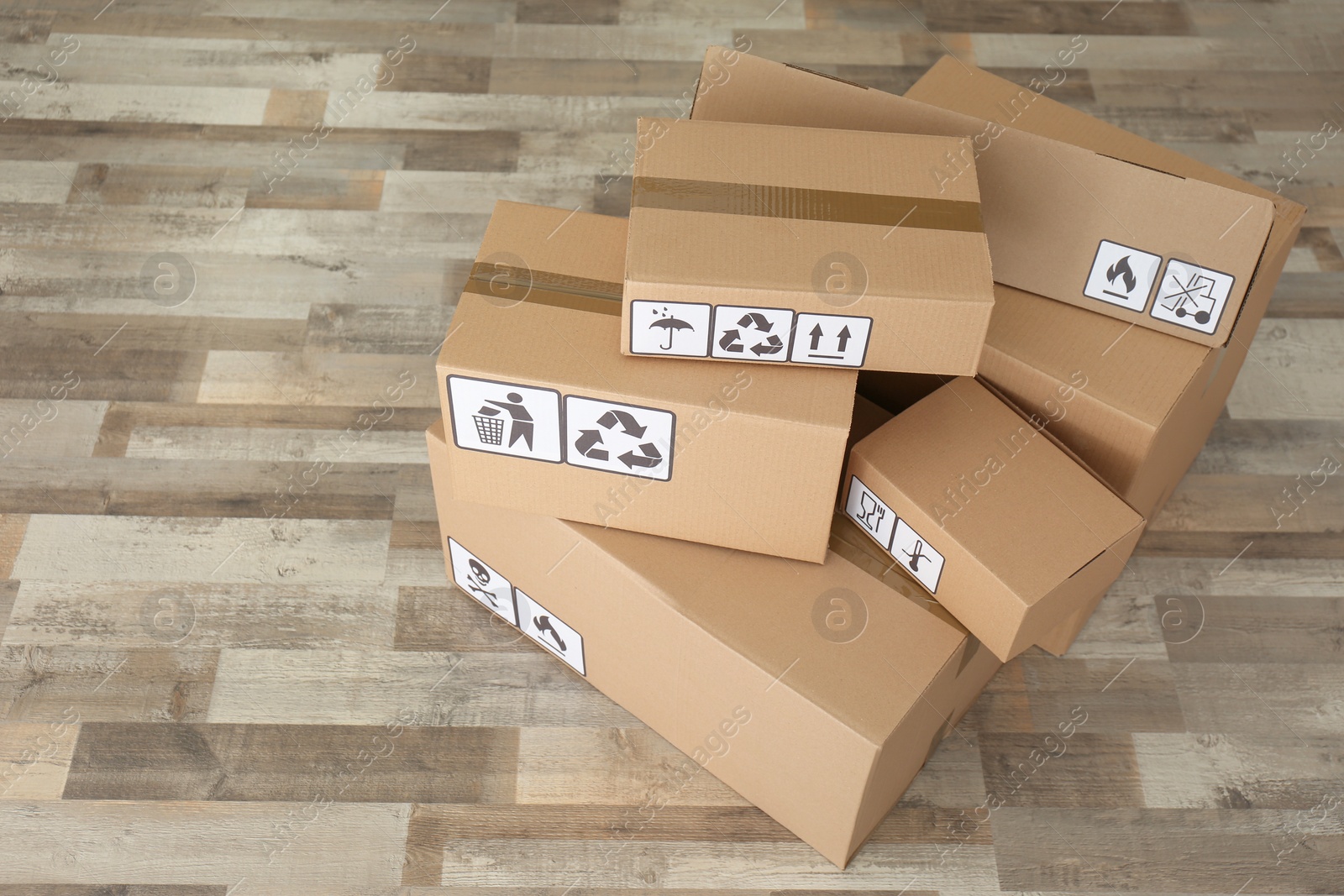 Photo of Cardboard boxes with different packaging symbols on floor. Parcel delivery