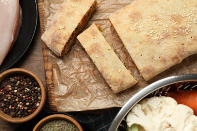 Photo of Delicious strudel with chicken and vegetables served on wooden table, flat lay