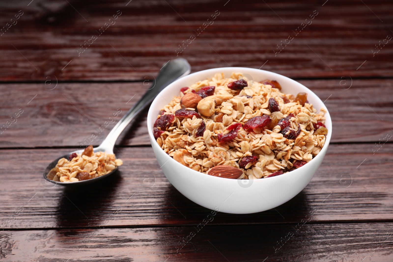 Photo of Tasty granola served with nuts and dry fruits on wooden table