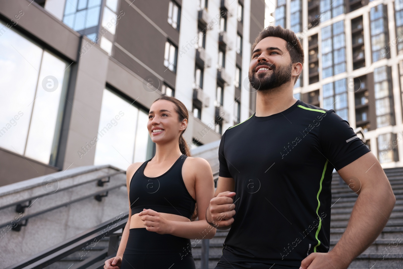 Photo of Healthy lifestyle. Happy couple running on steps outdoors, low angle view