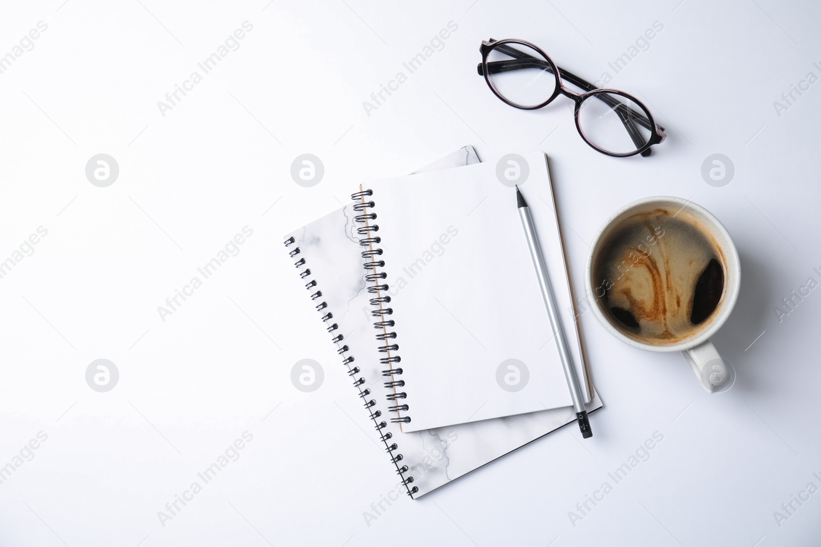 Photo of Notebooks with glasses and coffee on white background, top view. Space for text