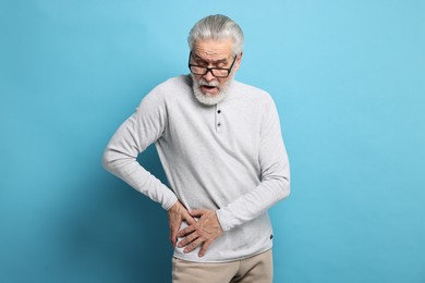 Arthritis symptoms. Man suffering from hip joint pain on light blue background