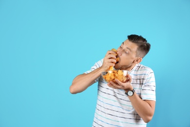 Photo of Man eating potato chips on color background. Space for text