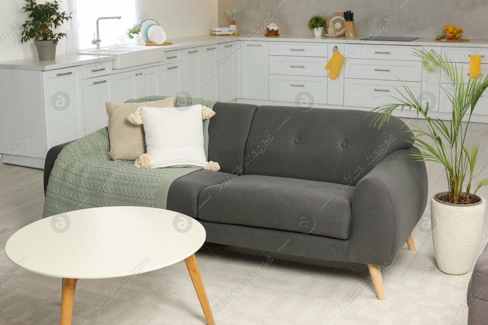 Photo of Gray sofa and white wooden table in kitchen