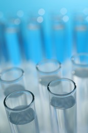 Photo of Many glass test tubes on light blue background, closeup