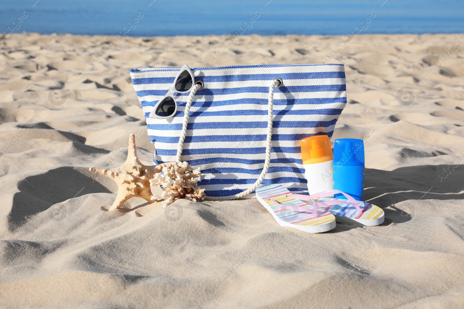 Photo of Set with stylish beach accessories on sand near sea