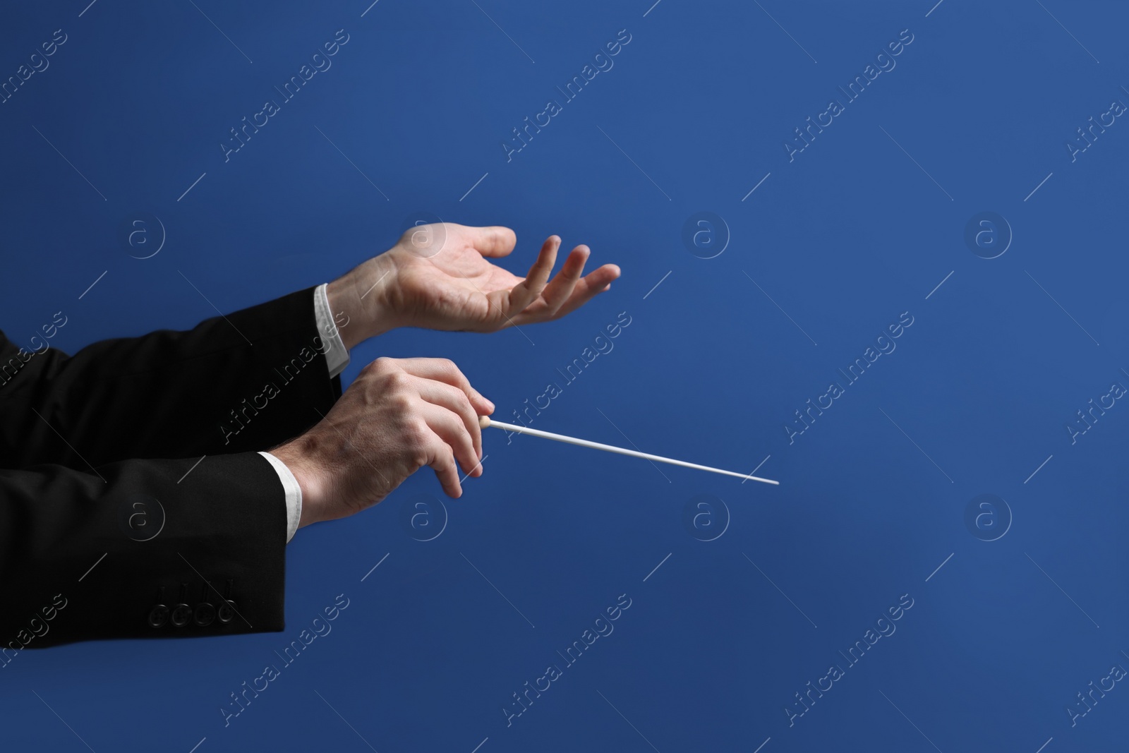 Photo of Professional conductor with baton on blue background, closeup