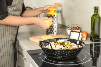 Photo of Woman cooking delicious risotto, closeup. Tasty recipe