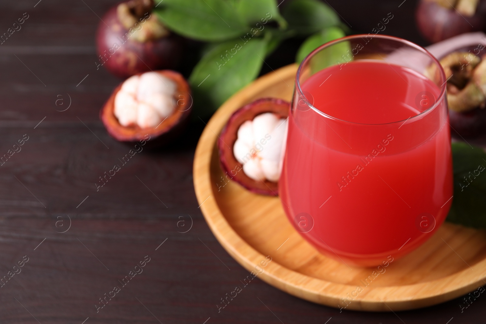 Photo of Delicious mangosteen juice in glass on wooden table. Space for text