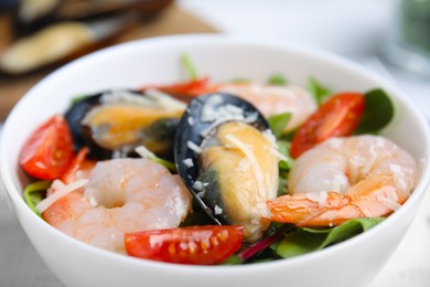 Photo of Bowl of delicious salad with seafood, closeup view