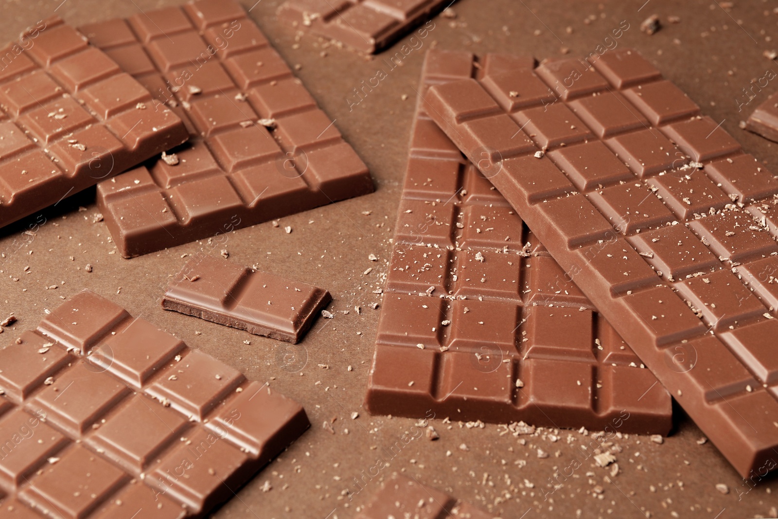 Photo of Pieces of tasty chocolate on brown background