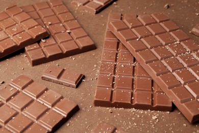 Photo of Pieces of tasty chocolate on brown background