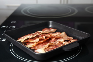 Slices of tasty fried bacon on kitchen stove