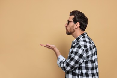 Photo of Handsome man blowing kiss on beige background. Space for text