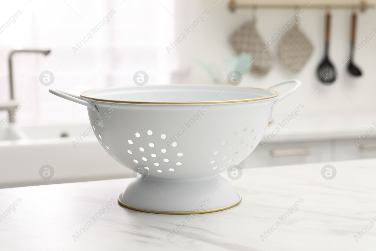 Photo of Clean colander on white marble table in kitchen