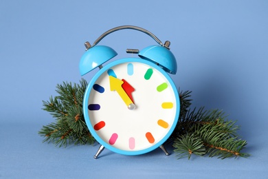 Alarm clock and fir branch on blue background. New Year countdown