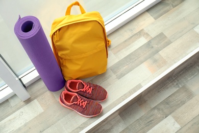 Photo of Sports bag and gym equipment on wooden floor near window