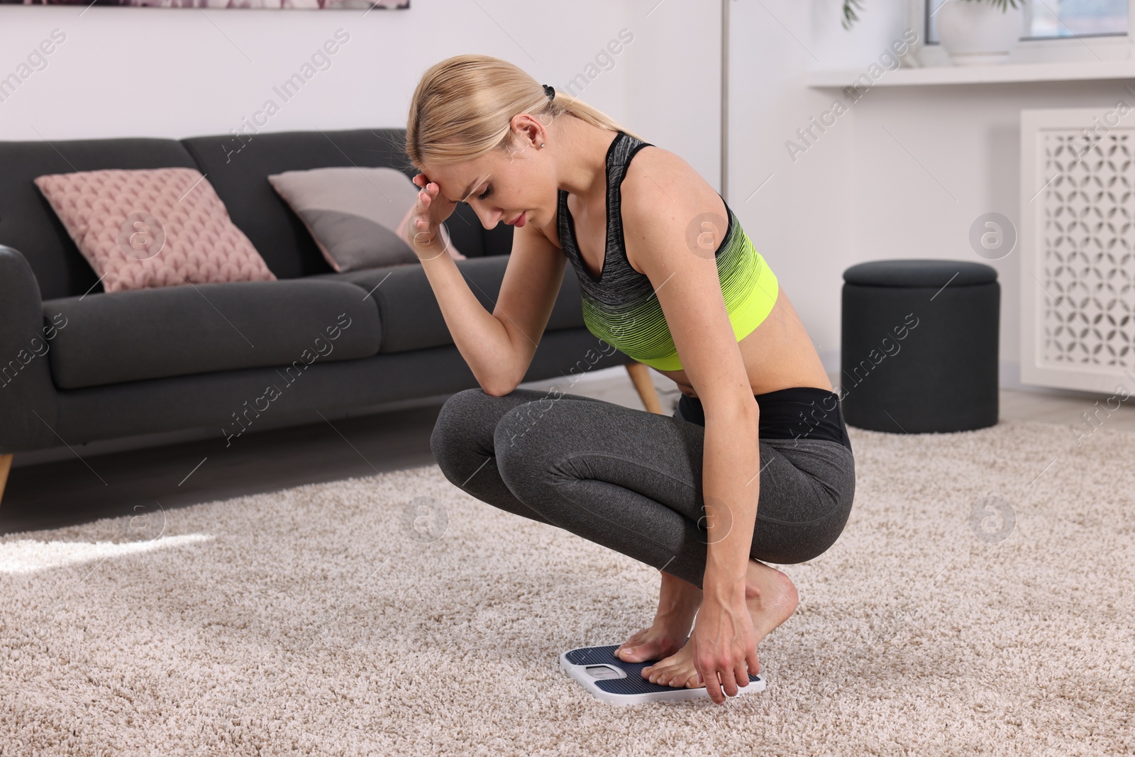 Photo of Worried woman on floor scale at home