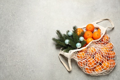 Photo of Christmas composition with fresh tangerines in mesh bag on light background, flat lay. Space for text